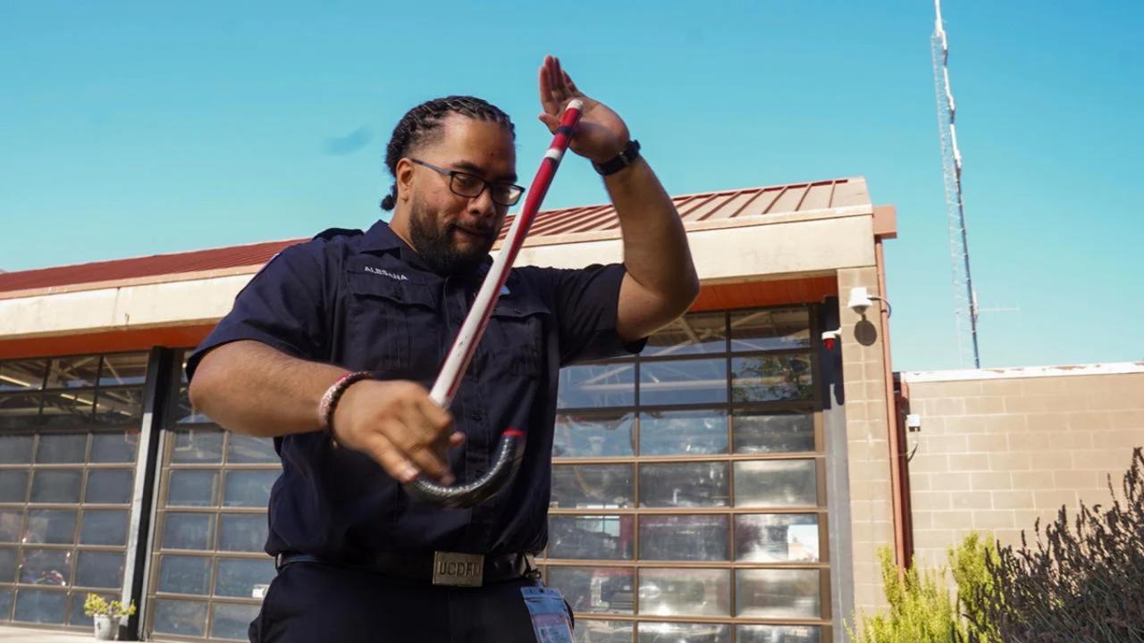 Abiel Malepeai, who received the UC President's Award for Outstanding Student Leadership for his advocacy for Pacific Islanders, shows off the cane of his fraternity outside the UC Davis Fire Department, where he serves as a student EMT.
