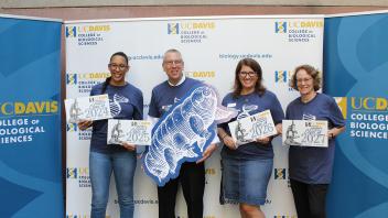UC Davis Biology staff hold class year signs and a large tardigrade cutout at a College of Biological Sciences event.