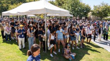 Hundreds of students gather under and around white tents on a sunny lawn during UC Davis College of Biological Sciences event.