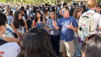 A faculty member in CBS t-shirt talking to a large group of students