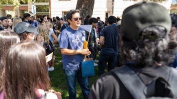 A faculty member in CBS t-shirt talking to a large group of students