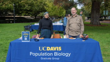 Two people stand behind a UC Davis Population Biology Graduate Group table at the campus Grad Student Fair.