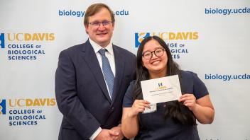 Two smiling people holding a certificate in front of UC Davis logos