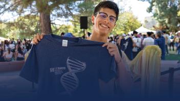 Student smiling and holding up a CBS t-shirt