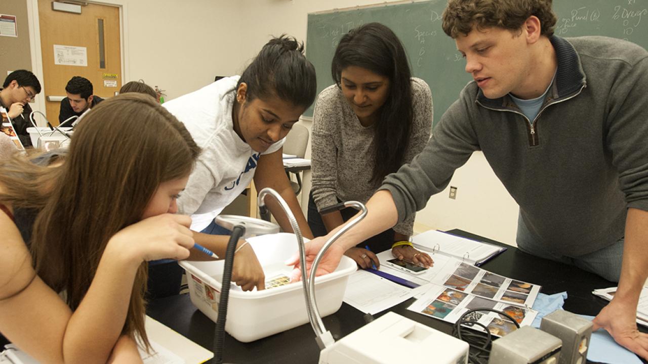 Group of students and instructor gathered around table