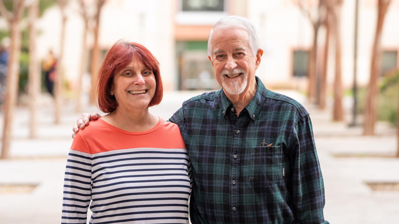 Tammy and Steve Conston standing outside the Green Hall courtyard with Esau Hall behind them. 