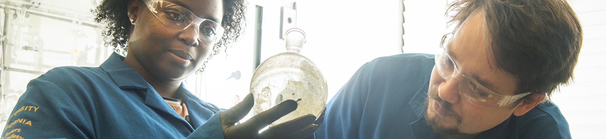 Student and researcher holding beaker